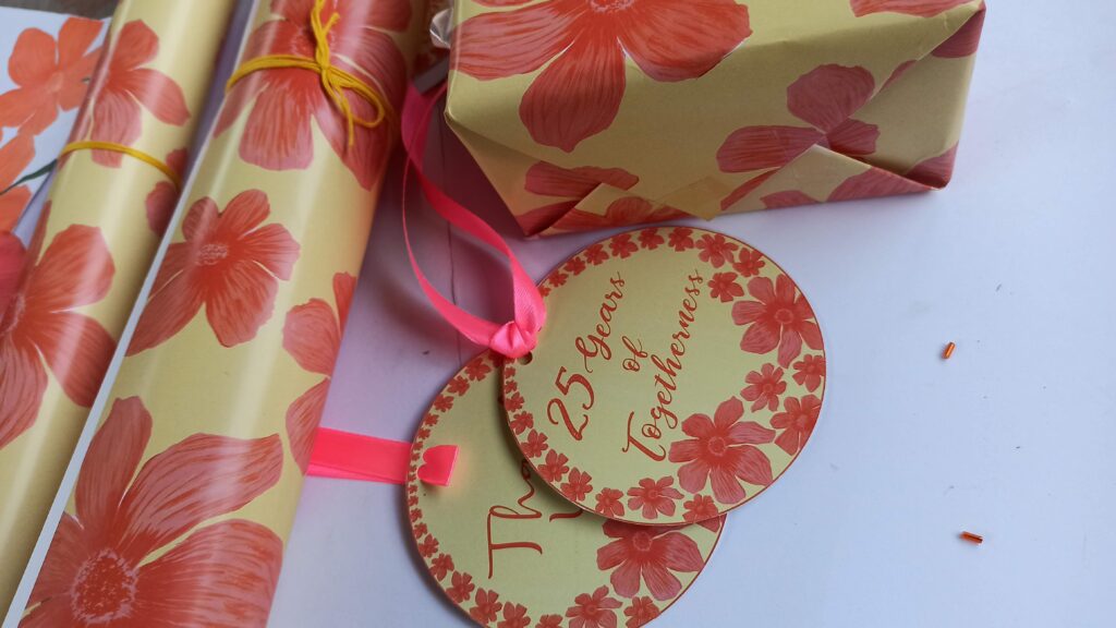 Gifts wrapped in customized paper with "25th Wedding Anniversary" text and elegant silver accents.